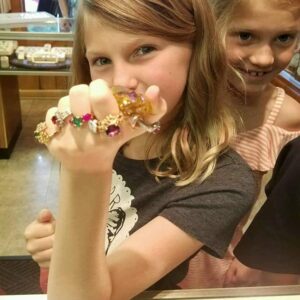 two excited kids holding up hands with rings set with gemstone from Gem Mountain