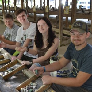 Four smiling visitors to Gem Mountain who are gem hunting