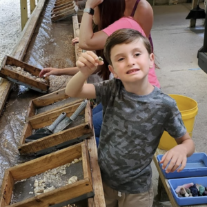 a young child showing off the gemstones he found while flume mining